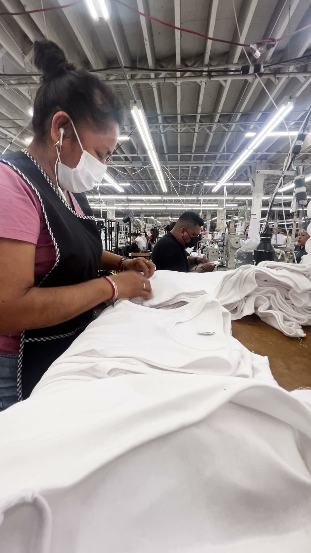 A worker at a table of white fabric at Los Angeles Apparel